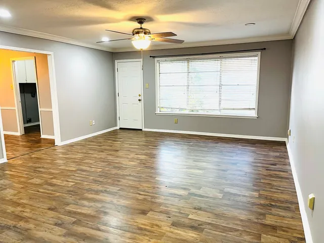 an empty room with wooden floor chandelier fan and windows