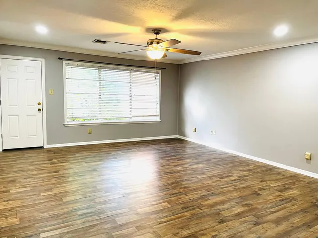 an empty room with wooden floor and windows