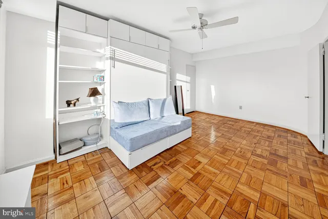 a living room with a bed and a walk in closet with wooden floor
