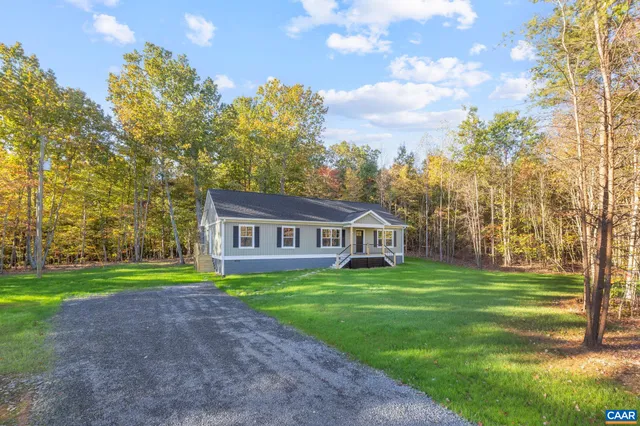 a view of a house with a big yard and large trees