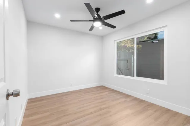 an empty room with wooden floor and a ceiling fan