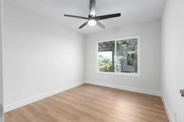 an empty space with wooden floor and a ceiling fan
