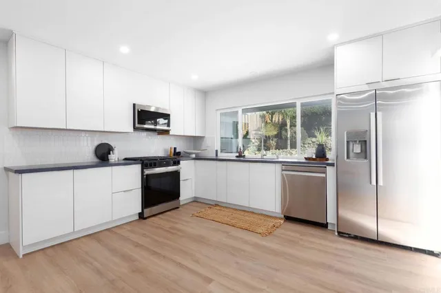 a kitchen with granite countertop a refrigerator cabinets and wooden floor