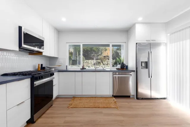 a kitchen with stainless steel appliances granite countertop a stove a sink and a refrigerator