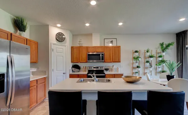 a kitchen with stainless steel appliances a sink a refrigerator and a counter top space