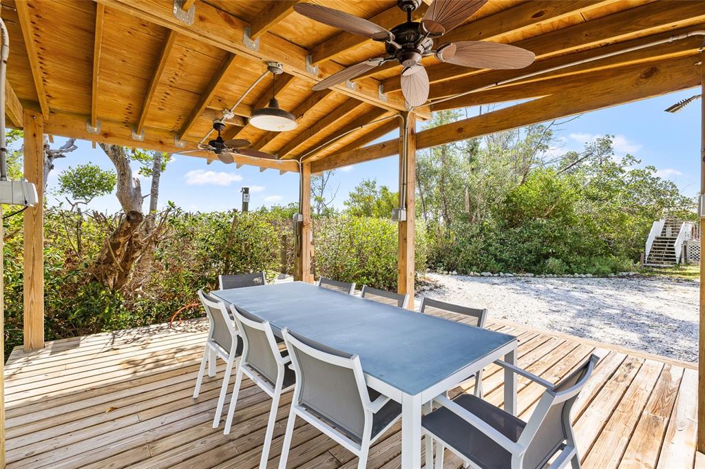 9664 Privateer Road Boca Grande, FL 33921 - Photo 44 of 66 a view of a patio with table and chairs with wooden floor and fence