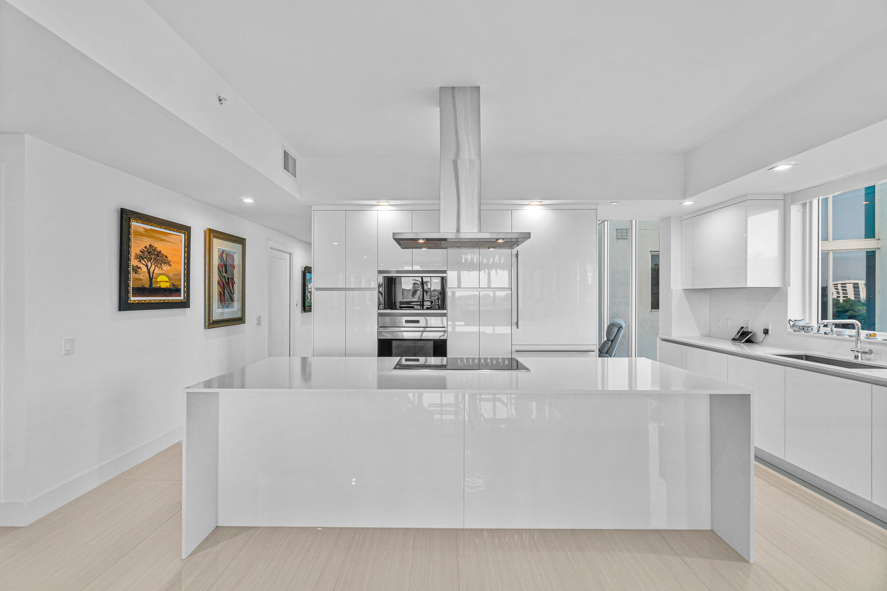 a large white kitchen with kitchen island granite countertop a sink a stove and a refrigerator
