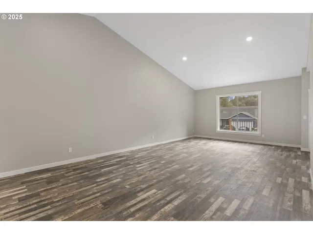 a view of an empty room with wooden floor and window