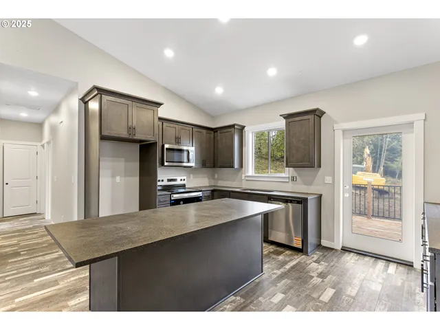 a kitchen with stainless steel appliances granite countertop a refrigerator a sink dishwasher a stove and white cabinets with wooden floor