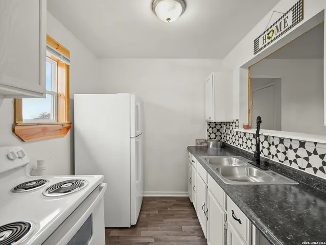 an empty room with wooden floor ceiling fan and windows