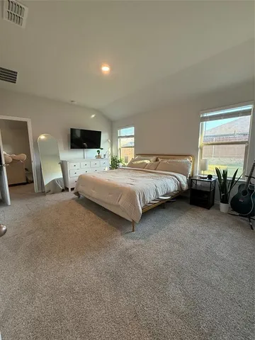 a spacious bedroom with a bed a couch and dresser