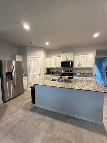 a large kitchen with stainless steel appliances granite countertop a refrigerator and a stove top oven