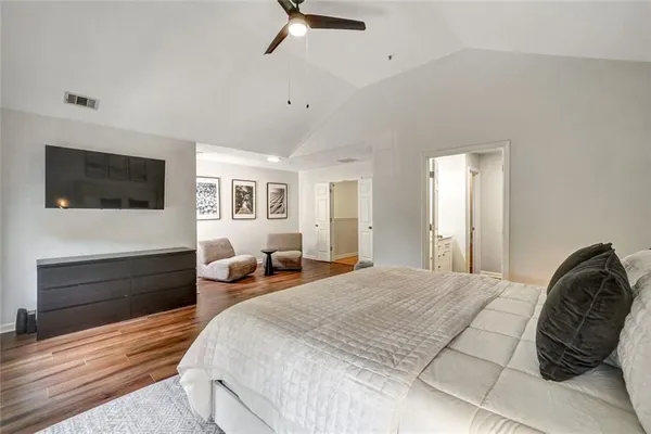 a bedroom with a bed a mirror on dresser and a flat screen tv