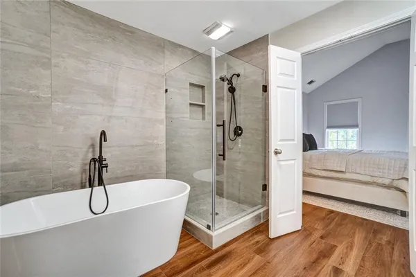 a bathroom with a tub a window and a glass door shower