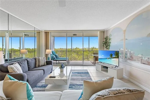 a living room with furniture kitchen view and a large window