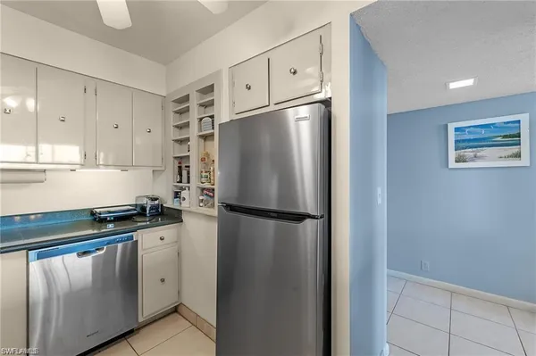 a kitchen with stainless steel appliances granite countertop a refrigerator a sink and white cabinets