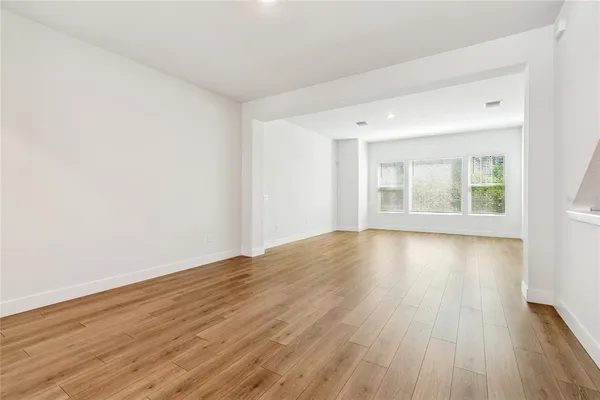 an empty room with wooden floor and windows