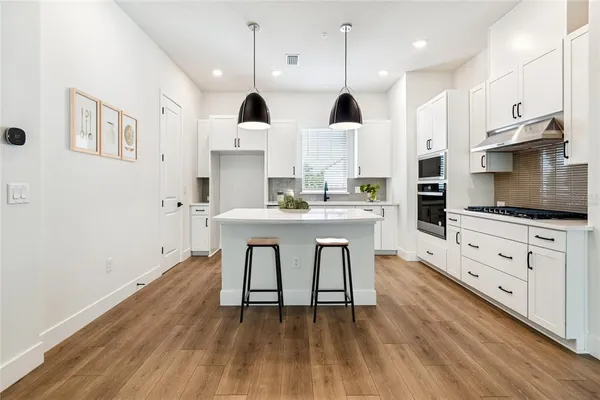 a kitchen with stainless steel appliances a kitchen island hardwood floor sink stove and granite counter top