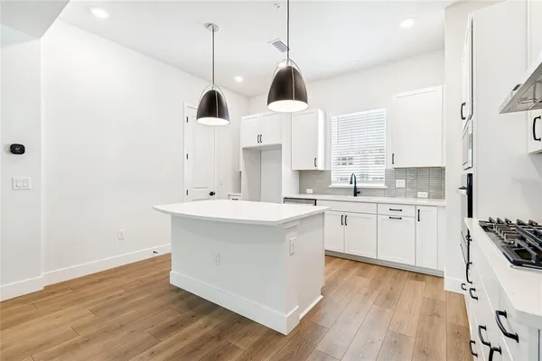 a kitchen with white cabinets stainless steel appliances a sink and a window