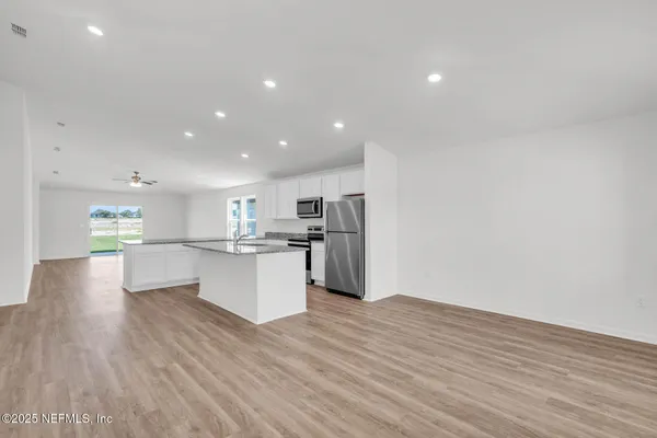 a view of kitchen with kitchen island wooden floors and stainless steel appliances