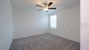 an empty room with a window and a fan