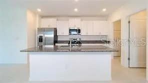 a kitchen with stainless steel appliances granite countertop a sink and a refrigerator
