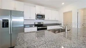 a kitchen with stainless steel appliances granite countertop a refrigerator a stove and a sink