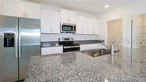 11142 Radiant Shr Loop San Antonio, FL 33576 - Photo 7 of 43 a kitchen with stainless steel appliances granite countertop a refrigerator a stove and a sink