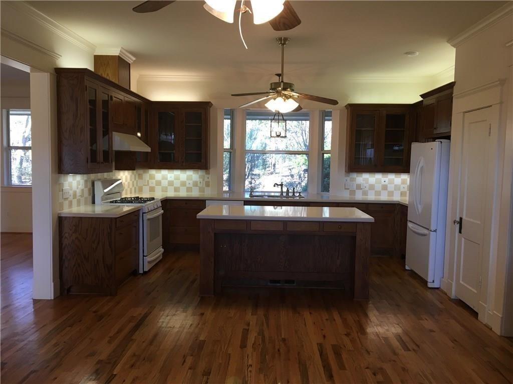 581 Country Club Road Fairview, TX 75069 - Photo 12 of 39 a room with kitchen island granite countertop wooden floors a sink stainless steel appliances and dining table