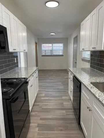 a large kitchen with granite countertop a stove sink and cabinets
