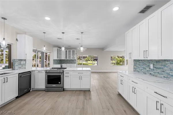 a white kitchen with stainless steel appliances granite countertop a stove and a sink