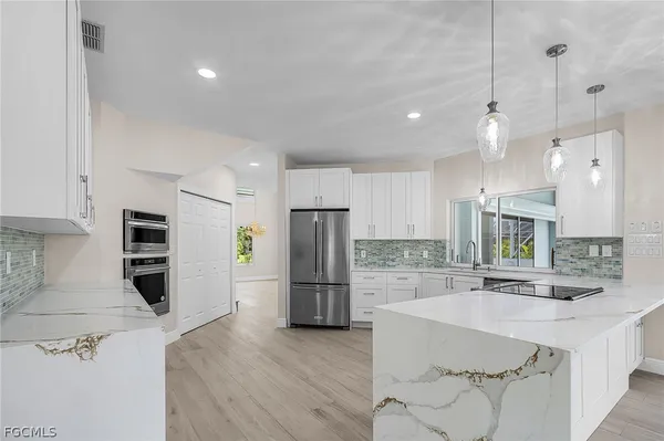 a kitchen with stainless steel appliances granite countertop a refrigerator a sink a stove and a oven