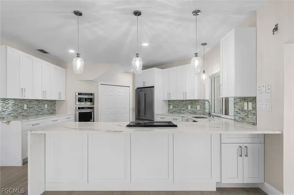 a kitchen with stainless steel appliances kitchen island granite countertop a sink a stove and a refrigerator
