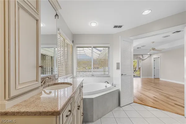 a bathroom with a granite countertop tub sink and mirror