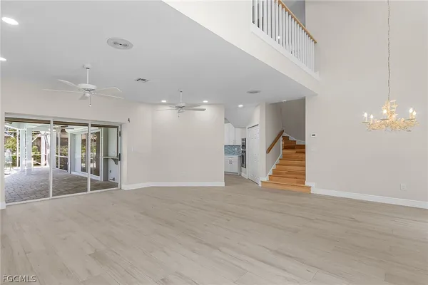 a view of an empty room with wooden floor and a chandelier