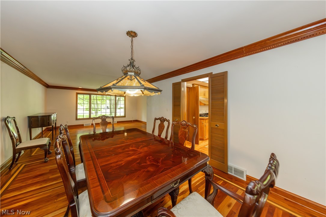 25001 Letchworth Road Beachwood, OH 44122 - Photo 7 of 50 Dining area featuring wood-finish flooring with perimeter inlay, ornate crown molding, and a decorative ceiling light fixture