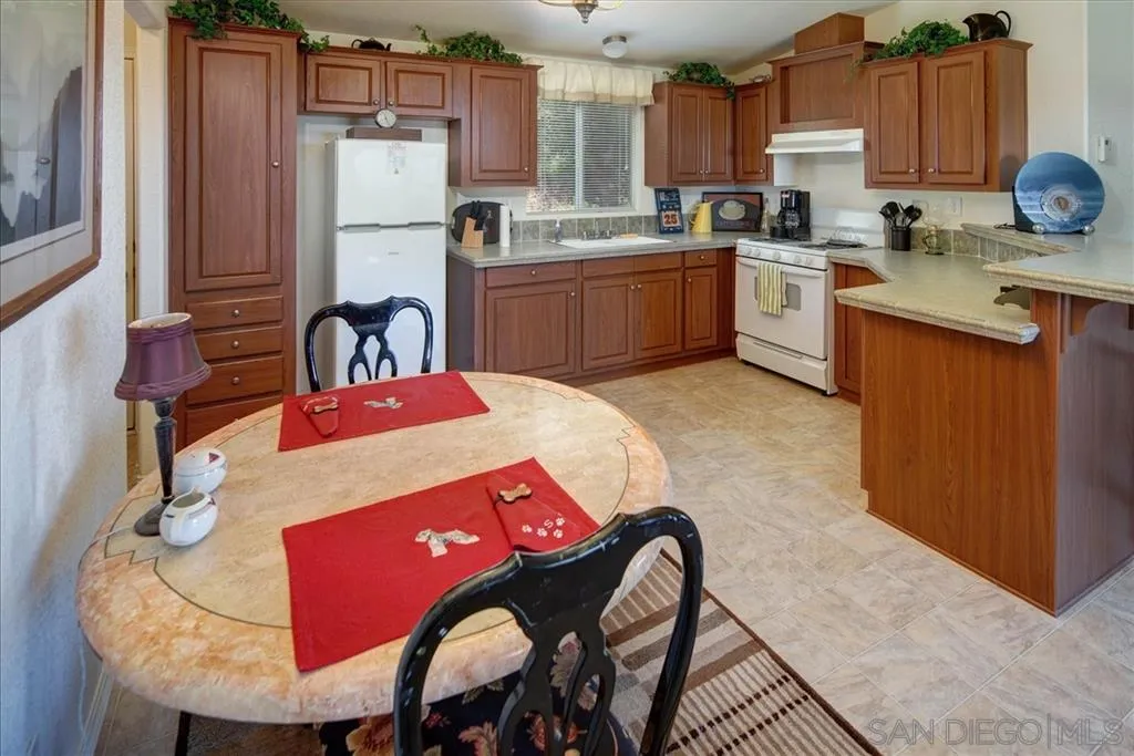 5495 Acorn Patch Road Julian, CA 92036 - Photo 12 of 23 a kitchen with stainless steel appliances granite countertop a sink dishwasher a stove a refrigerator with a dining table and chairs