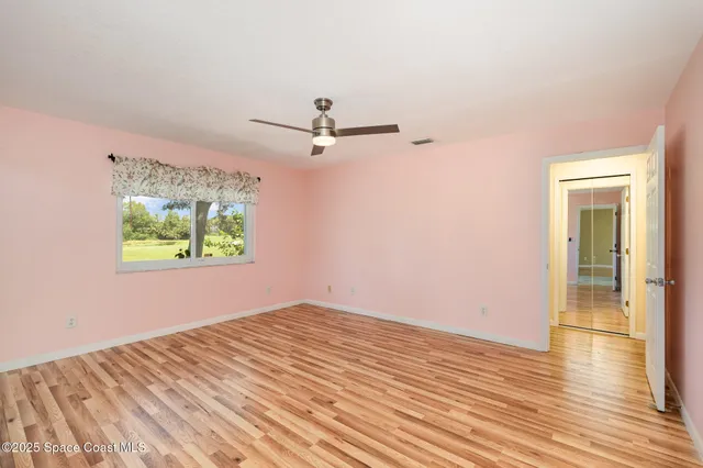 a view of a room with wooden floor and a ceiling fan