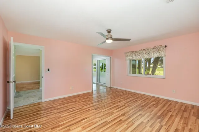 a view of an empty room with window and wooden floor