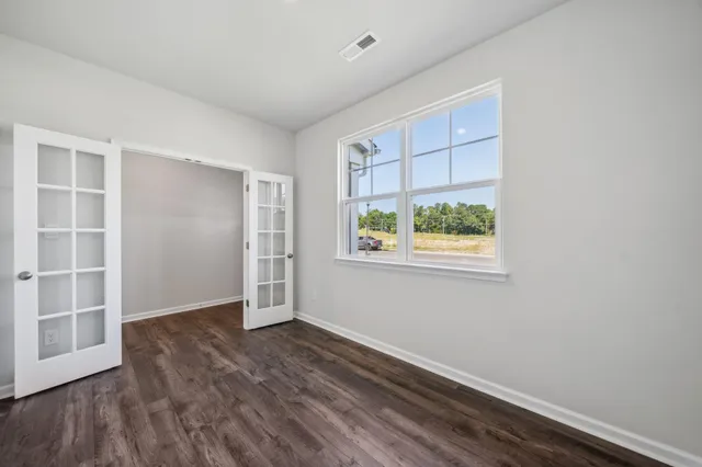 an empty room with wooden floor and windows