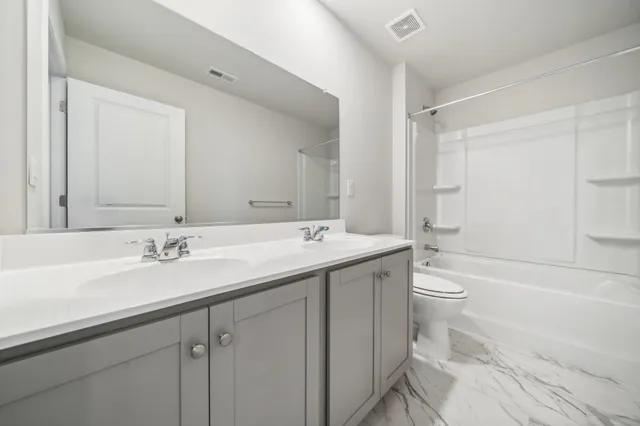 a bathroom with a bathtub shower sink vanity mirror and toilet