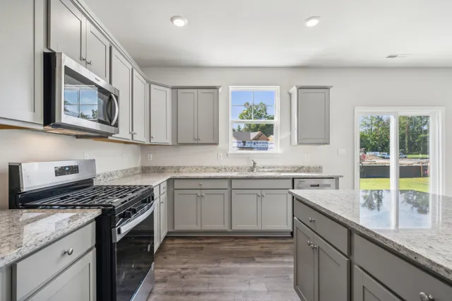a kitchen with stainless steel appliances granite countertop a stove a sink and a microwave
