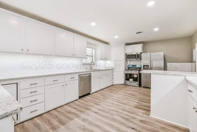 a kitchen with granite countertop white cabinets and stainless steel appliances