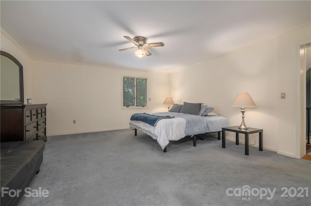 15 Doubleday Road Tryon, NC 28782 - Photo 23 of 46 a spacious bedroom with a bed a chandelier and a couch