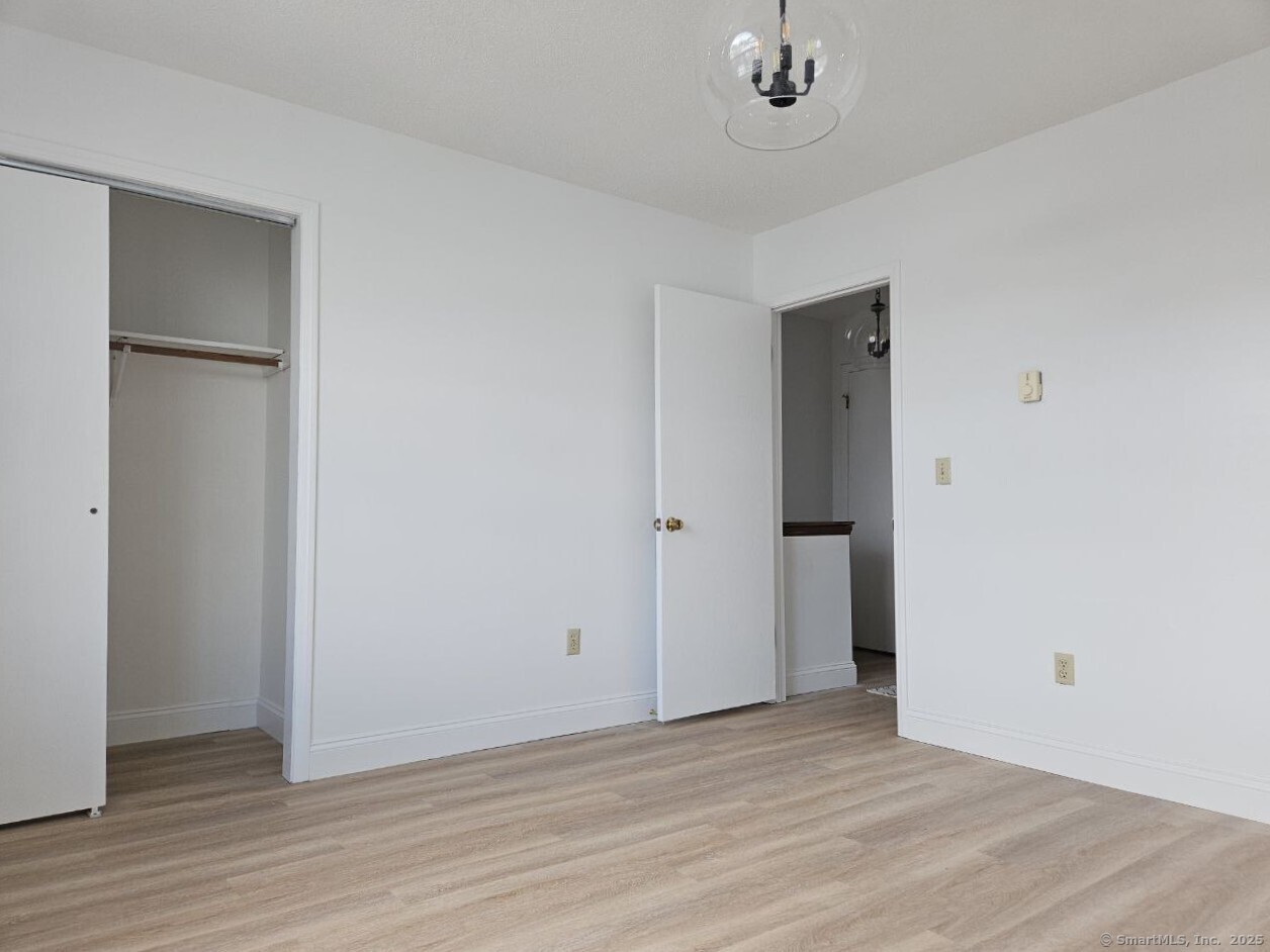 975 Meriden Road, Unit 11 Waterbury, CT 06705 - Photo 6 of 27 a view of an empty room with wooden floor and a window