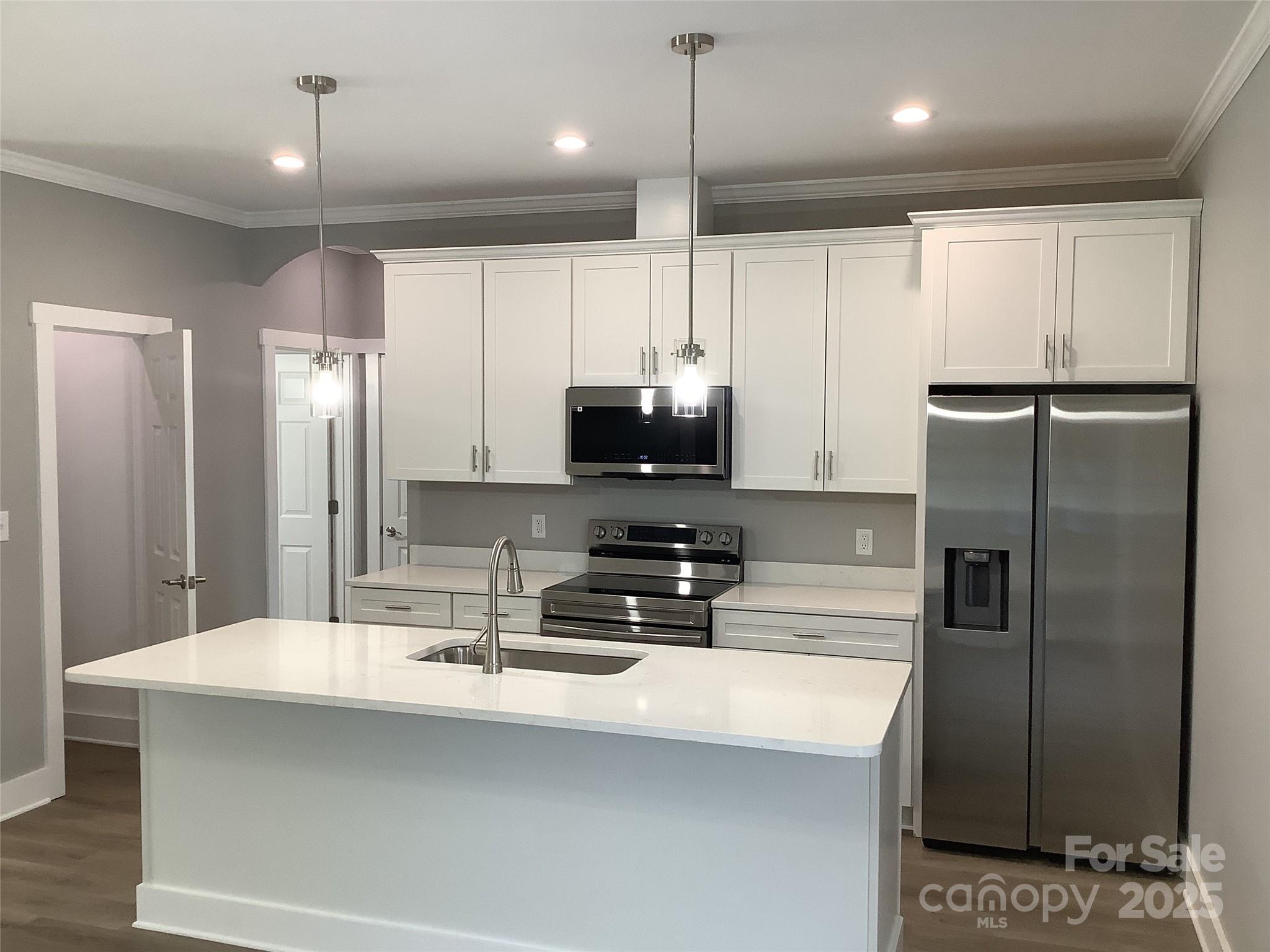 302 West 2nd Street Lowell, NC 28098 - Photo 4 of 17 a kitchen with kitchen island a counter space a sink and refrigerator