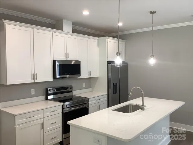 a kitchen with stainless steel appliances granite countertop a sink a stove and a refrigerator