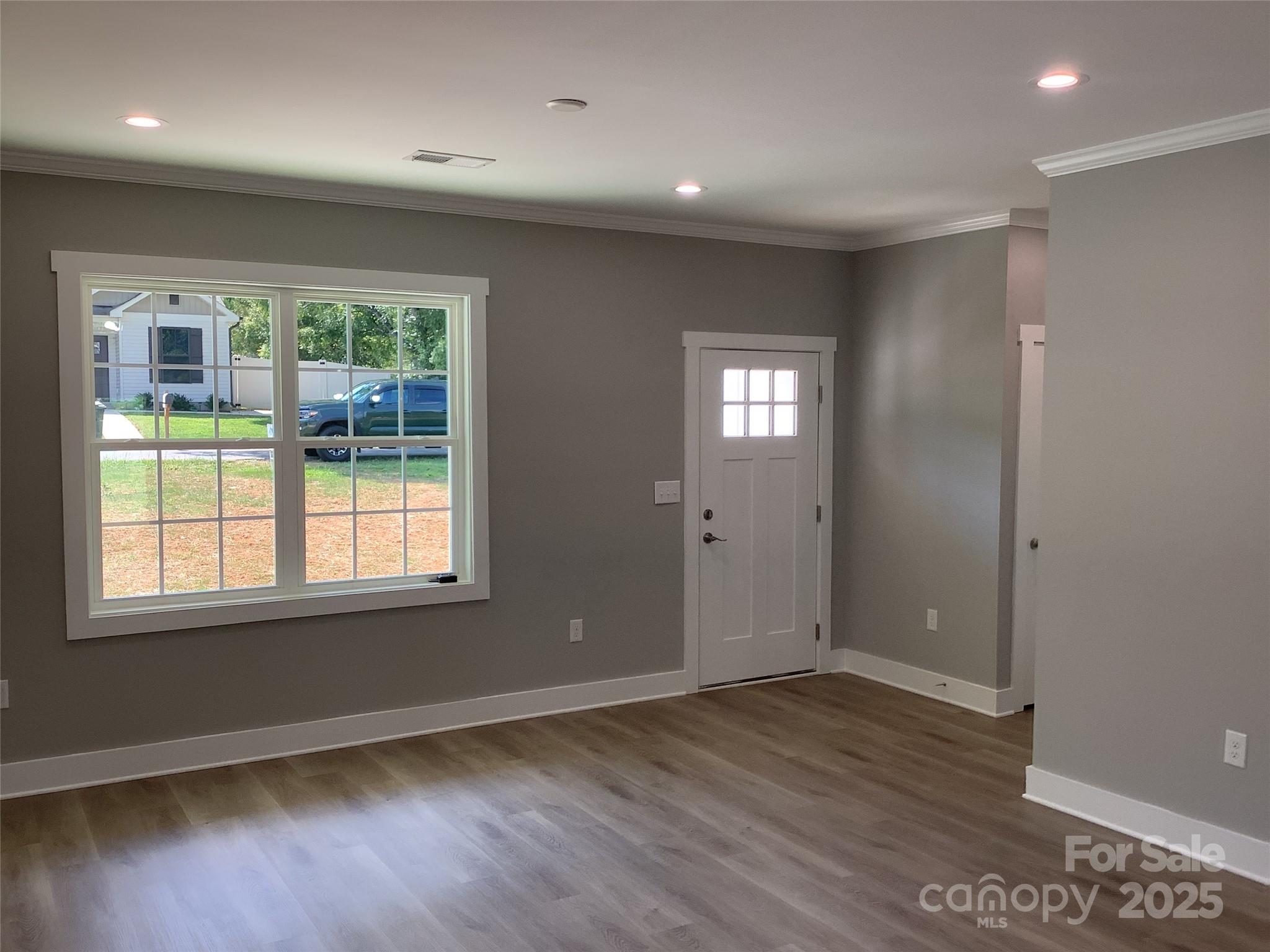302 West 2nd Street Lowell, NC 28098 - Photo 6 of 17 an empty room with wooden floor and windows