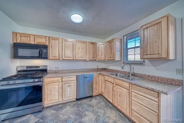 a kitchen with granite countertop white cabinets sink and stainless steel appliances