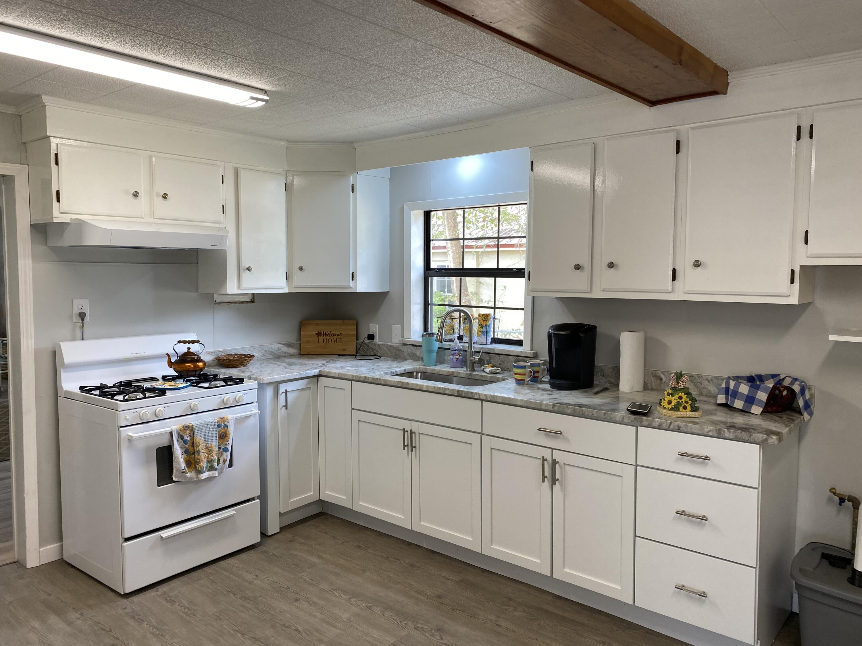 597 South Wilson Street Crestview, FL 32536 - Photo 7 of 16 a kitchen with granite countertop white cabinets and white appliances